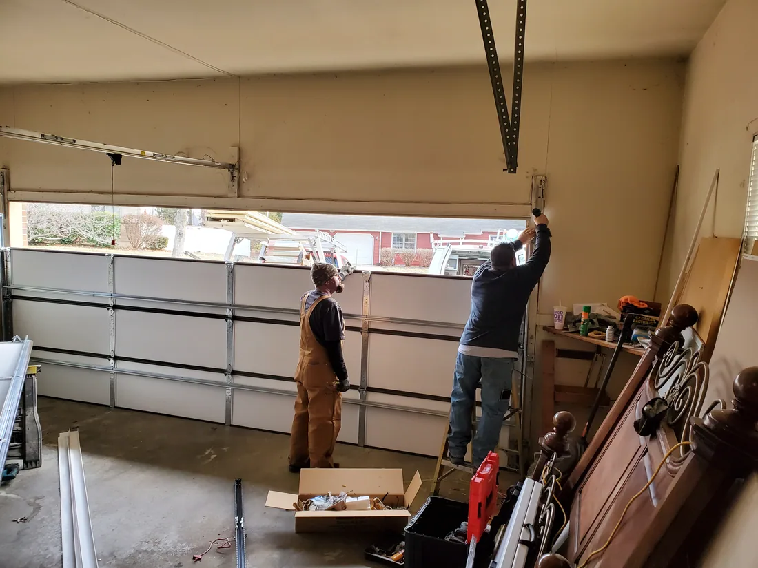 Garage door panel sections being lifted and joined during a full new door installation