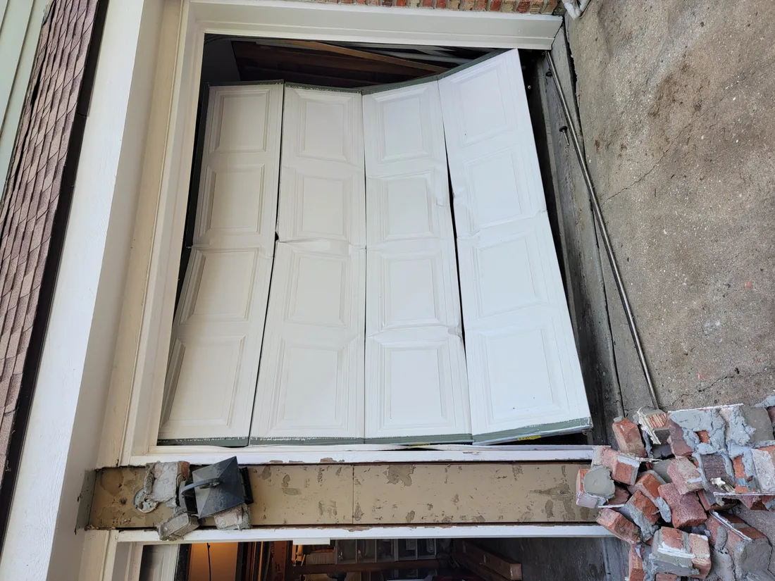 Garage door that jumped off its track — GDM KC technician resetting the rollers and rail